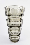 MOSER  DESIGN JOSEF HORRMANN   LINDO FLOREIRO EM CRISTAL FUME COM LAPIDAÇÃO OPTICA EM FACETAS ESTILO E ÉPOCA ART DECO. LAPIDAÇÃO GEOMÉTRICA COM EFEITOS OPTICOS. UMA DAS PRODUÇÕES MAIS MARCANTES DA CRISTALERIE MOSER QUE FOI CONCEBIDA SOB ENCOMENDA AO DESIGNER JOSEFF HOFFIMAN. IMPECÁVEL ESTADO DE CONSERVAÇÃO. OS VASOS JOSEF HORRMANN PARA MOSER SÃO ALTAMENTE COLECIONÁVEIS E SÃO OFERTADOS POR  IMPORTANTES CASAS LEILOERIAS COMO A SOTHEBYS (https://sothebyshome.com/moser-glassworks-art-deco-style-heavy-crystal-smokey-vase-acc-50027-37433.html) ÁUSTRIA, DEC. DE 1930. 25 CM DE ALTURA.NOTA: Josep Hoffmann foi um arquiteto e designer europeu nascido na Áustria em 1870. Junto com Joseph Maria Olbrich, ele fundou a Vienna Secession em 1897 junto com Gustav Klimt e Koloman Moser (CRISTALERIE MOSER). O estilo do arquiteto, com o tempo, se tornou mais sóbrio e abstrato, limitando-se a estruturas funcionais. Alguns produtos projetados por ele se tornaram clássicos, como a cadeira Sitzmachine (Máquina de Sentar, 1905). Em 1906, ele construiu o Sanatório Purkersdorf, o qual serviu como precedente importante e inspiração para a Arquitetura Moderna no século XX. No entanto, a obra-prima de sua carreira foi o Palais Stoclet (Palácio Stoclet, 1905-11), construído em Bruxelas, que também é considerado o exemplar mais completo do Sezessionstil (estilo Secessão). O edifício, encomendado por um rico banqueiro, está repleto de pinturas de Klimt e foi totalmente mobiliado e equipado com produtos desenvolvidos pela Wienner Werkstätte. A torre está coroada por quatro figuras de cobre do escultor alemão Franz Metzner.