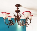 SUNTUOSO LUSTRE EM BRONZE COM CÚPULAS EM VIDRO ARTÍSTICO LEITOSO E VERMELHO. O BRONZE DE EXCEPCIONAL QUALIDADE. DOTADO DE CINCO LUMES. EUROPA, INICIO DO SEC. XX. 68 CM DE DIAMETRO X 60 CM DE ALTURA.
