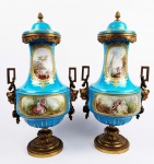 SEVRES  PALACIANO PAR DE ÂNFORAS EM PORCELANA COM GUARNIÇÃO EM BRONZE ORMOLU. FUNDO NA TONALIDADE AZUL CELESTE. DECORADO COM RESERVAS CONTENDO CENAS DE PAISAGENS MARINHAS E IDÍLICAS COM FLORESTA. NA PARTE ANTERIOR RESERVAS VEGETALISTAS COM LUXURIANTES FLORES E RAMAGENS. AS RESERVAS SÃO EMOLDURADAS POR ESMALTES PEROLADOS EM RELEVO SIMULANDO RUBIS E REALÇADAS POR LINDAS GUIRLANDAS EM OURO. O MAGNÍFICO BRONZE TEM ALÇAS REMATADAS POR CARIÁTIDES E FLORES. SÃO FORMIDÁVEIS E BELISSIMAS! FRANÇA, MEADOS DO SEC. XIX. 39 CM DE ALTURA