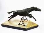 MAX LEvERRIER  CHEVAL FOUQUE  LINDA ESCULTURA EM BRONZE REPRESENTANDO FIGURA DE CAVALO SALTANDO SOBRE OBSTÁCULO. A BASE É MAGNIFICA MISTA EM ONIX DE DUAS CORES E MÁRMORE NEGRO. FRANÇA, INICIO DO SEC. XX.  58 CM DE COMPRIMENTONOTA: Max le Verrier nasceu em Neuilly-sur-Seine, perto de Paris, em 1891. Desde muito jovem mostrou-se muito promissor como artista e escultor; e depois de servir no exército francês durante a Primeira Guerra Mundial, ele estudou na Ecole des Beaux-Arts em Genebra. Durante seus estudos na Suíça, ele conheceu seus colegas escultores Pierre le Faguays e Marcel Bouraine, que se tornaram amigos íntimos e com quem colaborou durante grande parte de sua vida. Após completar seus estudos, le Verrier voltou à França em 1919 e fundou seu próprio estúdio em Paris. Foi nessa época que ele criou sua primeira escultura popular - o famoso 'Pelicano' - que foi a primeira de uma longa linha de figuras de animais que levaram seu nome. Le Verrier foi premiado com uma medalha de ouro por suas esculturas na Paris l'Exposition des Arts Décoratifs et Industriels de 1925 (a famosa exposição da qual o termo 'Art Deco' foi derivado). Em 1926, le Verrier abriu sua própria fundição, fundindo peças para uma ampla gama de escultores franceses da época, incluindo Pierre Le Faguays, Marcel Bouraine, Janle, Denis e Charles. Desde o início, ele ganhou reputação pelo trabalho de altíssima qualidade, detalhamento excepcional e precisão dos itens que sua empresa produzia. Ao mesmo tempo em que dirigia sua fundição, le Verrier continuou a esculpir suas próprias criações e, na década de 1920, tornou-se famoso por seus estudos sobre a mulher, como parte do fascínio da era Art Déco pela forma feminina ideal. Suas figuras femininas são caracterizadas por seu porte atlético e uma simetria perfeita; e são altamente consideradas e muito procurados. Le Verrier continuou trabalhando ao longo dos anos 1930 - recebendo uma medalha de honra na Exposição Internacional de Paris em 1937 - antes de ser preso em 1944 por suas atividades de resistência contra o regime apoiado pelos nazistas. Ele reabriu seu estúdio após a Segunda Guerra Mundial e continuou a esculpir até sua morte em 1973