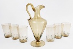 VITTORIO ZECCHIN PARA VENINI  PRODUÇÃO INICIAL DO MURANO MODERNO DO INICIO DO SEC. XX ESTILO INAUGURADO POR ZECCHIN. LINDO DECANTER COM SEIS COPOS EM VIDRO ARTÍSTICO DE MURANO DO DESIGNER VITTORIO ZECCHIN. COPOS COM FEITIO FACETADO E O DECANTER DECORADOS COM PROFUSA APLICAÇÃO DE PÓ DE OURO E COM RELEVOS PUNTIFORMES EM AZUL CELESTE. O CONJUNTO TEM SEIS COPOS E UM DECANTER (UM CONJUNTO IDÊNTICO A ESSE SERÁ APREGOADO NO LOTE A SEGUIR) ITÁLIA, DEC. 20. 13 X 8 CM (COPO) E 30 CM DE ALTURA (DECANTER)NOTA: Vittorio Zecchin , artífice de Murano.  Filho de Louis, já um fabricante em vidro de Murano , é formado pela Academia de Belas Artes de Veneza . Em 1914 apresenta à XI Bienal , alguns vidros fabricados na vidraria Barovier . De 1921 a 1925 é diretor artístico da empresa Muranesi Vidros Soprados Cappellin Venini & C. para a qual cria peças clássicas em vidro claro e com cores delicadas. Inspirados no estilo pictórico do século XVI dos pintores venezianos, esses vasos foram os primeiros exemplos de obras modernas em vidro de Murano . Depois da experiência com Cappellin Venini, colabora com as vidrarias Salir (1932-1938), Barovier Seguso Ferro (1933-1934) e Fratelli Toso (1938). Durante os anos trinta e na última década de sua vida, ele também se dedicou ao ensino colaborando com vários institutos profissionais venezianos, incluindo a " Escola para a Indústria do Vidro " de Murano (em 1934) e a escola para aprendizes de vidro "Abate Zanetti" (a partir de 1936).