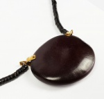 MIRIAM MAMBER  COLAR DE SEMENTES COM PINGENTE DE GRANDE SEMENTE REMATADA EM OURO 18K. BELO DESIGN. O COLAR TEM 56 CM DE COMPRIMENTO.NOTA: Filha de imigrantes europeus que se estabeleceram em solo brasileiro após a Segunda Guerra Mundial, Miriam passou a infância numa pequena cidade de Santa Catarina, retirando da natureza e do armazém de seus pais a matéria-prima de suas primeiras criações. Não por acaso, seu trabalho consiste em buscar inspiração nos lugares menos evidentes, criando peças transgressoras e carregadas de simbologia. Nas mãos de Miriam, elementos como grãos de café, moedas, fósseis, folhas e partes de objetos arqueológicos unem-se a pedras e metais nobres transformando-se em joias.  Suas jóias são mais que preciosas. São reinventos mágicos do mundo de materiais que misturados ao ouro, a prata e a diamantes se tornam únicos. Durante quase 35 anos Miriam Mamber criou mais de 3.000 mil peças exclusivas. As joias de design exclusivo são reinventos mágicos do mundo de materiais - sementes, vidro, pedras, lavas, meteoritos que, quando misturados ao ouro, a prata e a diamantes se tornam únicos. Sua formação em História da Arte, Arqueologia e Jornalismo serviu para construir essa plataforma criativa com foco no momento atual. Publicou o livro Miriam Mamber, em 2014, contando toda a sua trajetória. Dentre os prêmios recebidos destacam-se XII e XIII Bienal; Tahitian Pearl Trophy, Mitsukoshi e Ushiara (Japão); Bienal do Desing; Jóias da Cor do Brasil.