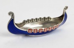 BARCO VIKING EM PRATA DE LEI COM ESMALTES NA TONALIDADE AZUL E VERMELHA. BELO EXEMPLAR DE TECNICA DE OURIVESSARIA COM ARREMATES EM ESMALTE. PROVAVELMENTE FINLÂNDIA, INICIO DO SEC. XX. 16 CM DE COMPRIMENTO.