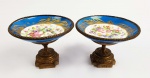 SEVRES  BELO PAR DE CORBEILLES EM PORCELANA E BRONZE ORMOLU. A PORCELANA TEM FUNDO NA TONALIDADE AZUL COBALTO E RESERVA PROFUSAMENTE DECORADA COM FLORES. ARREMATES EM OURO. O PÉ EM BRONZE ORMOLU TEM DECORAÇÃO COM LAURÉIS. ESTILO E ÉPOCA IMPÉRIO. FRANÇA, CIRCA DE 1860. 14,5 CM DE DIAMETRO