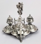 GRANDE TINTEIRO EM PRATA DE LEI DECORADO COM FIGURA DA DEUSA GREGA NICE, A DEUSA DA VITÓRIA. A DEUSA É REPRESENTADA ASSENTE SOBRE GLOBO CINGINDO ESPADA E UMA PALMA. EM CADA LADO DA ESCULTURA UM GRANDE FRASCO PARA TINTA. PORTA PENAS NA PARTE ANTERIOR DO TINTEIRO. ASSENTE SOBRE TRÊS PÉS DECORADOS COM HOMEM VERDE. POSSUI ESCUDELA COM INICIAIS DR. JCR. EUROPA, SEC. XIX. 29 CM DE ALTURA. 715G