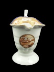 CIA DAS INDIAS  COM VISTA PEQUENA  RARA CREMEIRA DE MODELO DITO ELMO INVERTIDO EM PORCELANA COMPANHIA DAS INDIAS. REINADO JIAQING (1796-1820). BORDA COM BARRADO EM RICO OURO REMATADO POR LINHAS ROUGE DE FEUR FORMANDO ELEMENTOS GEOMÉTRICOS. O BARRADO É REALÇADO POR FRISO EM AZUL COBALTO E DECORADO COM RESERVAS COM ELEMENTOS FLORAIS, PÁSSAROS E PAISAGENS. NO CORPO MEDALHÃO COM VISTA PEQUENA REPRESENTANDO PAISAGEM EUROPÉIAS. BASE GOMADA FINALIZANDO EM PÉ CIRCULAR.  CHINA, SEC. XVIII. 16 X 11 CM