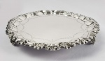 PRECIOSA SALVA EM PRATA DE LEI ESTILO E ÉPOCA DONA MARIA I COM MARCAS PARA CIDADE DO PORTO (P COROADO) E MARCAS DO PRATEIRO LUIZ ANTÔNIO TEIXEIRA COELHO (MOITINHO PAG. 265) CITADO ENTRE 1768-1784. ELEGANTE BORDA RECORTADA COM GUIRLANDA FLORAL RELEVADA. PLANO COM GUIRLANDA VEGETALISTA. MAGNÍFICOS PÉS ALTOS CONSTRUÍDOS COM VOLUTAS E FENESTRAS. PORTUGAL, SEGUNDA METADE DO SEC. XVIII. 32 CM DE DIAMETRO. 835G
