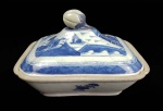 CIA DAS INDIAS - CANTÃO BELA TERRINA  DE FEITIO  RETANGULAR CONSTRUÍDA EM PORCELANA UNDERGLAZE DO PERÍODO QIANLONG (1736-1795). BORDA COM BARRADOS EM AZUL FORMADOS POR FIGURAS GEOMÉTRICAS. RESERVA COM CENAS LACUSTRES, COM BARCOS, PONTE E PAGODES.  TAMPA TEM FEITIO DE  FRUTO. CHINA, SEC. XVIII. 25  CM DE COMPRIMENTO.