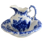 Jarro e bacia de porcelana inglesa. Fundo de superfície branca com intensa decoração floral em azul. No fundo as inscrições: Manhattan, Johnson & Bros Lt. Peça similar reproduzida na Encyclopedia of British Marke Pottery. Figura 2176. Página 355. 11 x 41 cm (bacia). 29 cm (jarro).