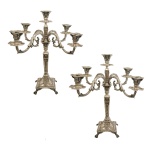 Par de candelabros para cinco velas, estilo Império, em prata brasileira repuxada e cinzelada, decorados com guirlandas e folhagens. Hastes no formato de colunas de secção quadrangular, encimadas por braços recurvos centralizando ponteiras. Bases apoiadas em pés de garra. Pseudo contraste da cidade do Porto do século XIX (1861-1869) e marcas de prateiro não identificado (Moitinho BR-113B, p.373 e BR25B pág. 348  c. 1861/69). 50 x 48 cm. 7k428 gramas.