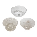 Lote constando de três centros de mesa circulares em cristal europeu, translucido e lapidado, sendo:  1 com decoração de flores (7 x 13 cm); 1 lapidado na borda (7 x 13,5 cm) e 1 com flores em relevo e selo Soya Japan (6 x 15,5 cm). Pertenceu ao Espólio de Vitória Dib Bachour.