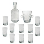 Conjunto de cristal translucido, apresentando decoração em geometrizados. Constando de: garrafa p/ whisky (15,5 cm); porta gelo (15 x 17 cm) e onze copos (11,5 cm). Pertenceu ao Espólio de Vitória Dib Bachour.