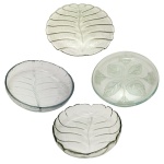 Conjunto de quatro peças de cristal, sendo: A) Duas saladeiras de cristal translúcidos e decoração similar a folhas. 8 x 31,5 cm / 5 x 26 cm. B)Dois pratos para bolo de cristal translucido, sendo um com decoração de folhagens (35 cm) e um na forma de grande folha (39 cm). Pertenceu ao Espólio de Vitória Dib Bachour.