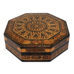 Caixa para joias marroquina em madeira nobre. Formato octogonal com decoração em marqueterie de madeiras claras e madrepérolas, predominando desenhos e forma geometrizadas. Tampa com reserva central na forma de estrelas. Interior forrado com veludo vermelho. 6,5 x 21,5 cm. Pertenceu ao Espólio de Vitória Dib Bachour.