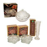 Conjunto de seis peças em cristal translucido e lapidado, sendo: A) Solifleur (15 cm); B) Conjunto de quatro covilhetes na forma de folha (11 cm); C) Bombonière de cristal apresentando decoração com flores em relevo. Soga Japan. 12 x 13,5 cm. Todas as peças acondicionadas em caixa. Peça novas e sem uso. Pertenceu ao Espólio de Vitória Dib Bachour.