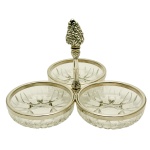 Petisqueira composta por três bowls circulares em cristal lapidado. Apresenta borda com frisos de metal liso e pega em forma de fruto. Largenhete Italy. 18 x 23 cm. Peça nova, sem uso acondicionada em caixa original. Pertenceu ao Espólio de Vitória Dib Bachour.