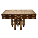 Tabuleiro marroquino para jogos com decoração em marqueterie de madeiras claras e madrepérola. Tabuleiro dobrável e de formato retangular. Base de madeira no mesmo estilo. Interior seguindo a mesma decoração. Acompanha pedras para jogo de dama. 8 x 52 x 26 cm (tabuleiro fechada). 52 x 52 cm (tabuleiro aberto). 24 x 26 cm (base). Pertenceu ao Espólio de Vitória Dib Bachour.