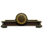 Relógio de mesa, funcionando. Apresenta caixa em madeira entalhada. Pés na forma de patas de leão. Mostrador em algarismo romano. Marca Silco. Mecanismo novo. Com chave. 27 x 80 x 17 cm. Pertenceu ao Espólio de Vitória Dib Bachour.