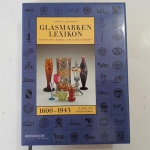 GLASMARKEN LEXIKON: SIGNATUREN, FABRIK UND HANDELSMARKEN 1600-1945 EUROPA UND NORDAMERIKA. Autor: Carolus Hartmann // Editora Arnoldsche, 1997 // O livro trata-se de um grande dicionário de marcas de fabricantes de vidros europeus e norte-americanos // Capa dura revestida em tecido, com sobrecapa e caixa para armazenamento // livro novo, altamente ilustrado com as marcas dos fabricantes, 1006 páginas