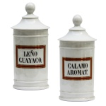 Par de potes de farmácia em porcelana da manufatura francesa. Superfície branca apresentando rótulos com as inscrições Leño Guayaco e Calamo Aromat. França.