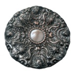 Medalhão em metal prateado em formato circular com profusa ornamentação de elementos concheados entre rocailles. Centro liso.  Séc. XX. 43 cm.
