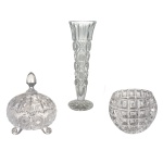 Conjunto de três peças de cristal europeu, translucido e lapidado, sendo: A) solifleur de cristal europeu, 20 cm. B) Porta geleia com tampa com três pezinhos (13 x 12 cm) / C) Pote sem tampa lapidados em losangos (9 x 10 cm).