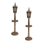 Par de lanternas de mesa em metal com resquícios de douração. Luminárias facetadas e envidraçadas, encimadas por ponteiras. Hastes lisas interrompidas ao centro por pequenos plateaux oitavados, apoiadas em bases circulares. Séc. XIX. 180 cm. 15 cm (base)