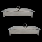 ST JAMES - Conjunto de dois suportes para refratário de metal espessurado a prata. Apresenta marcas do design brasileiro. Brasil. Séc. XX. 7 x 39 cm. Acompanha refratários.