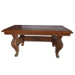 Mesa europeia em madeira nobre com tampo retangular liso realçado por frisos estilizados. Pernas largas e recurvas, ornamentadas por exuberantes folhagens esculpidas em alto relevo, reunidas por travessão reto centralizando adorno com motivo estrelar. 80 x 180 cm. Encontra-se na casa do comitente em Alphaville e deverá ser retirado com a orientação da organizadora do leilão.