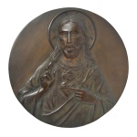 Placa religiosa em bronze cinzelado e patinado representando Sagrado Coração com imagem de Jesus. Assinada, possivelmente H.Trusi. Suporte para apoiar. 26 cm.