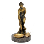 Escultura em metal polido e dourado representando figura feminina. 15 cm. Base 2 x 9,5 cm.