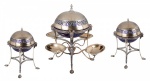 Elegante epergne em prata inglesa e interior em vermeil. Contraste da cidade de Londres. Letra data 1907/8. Marca de ourives HA & S. Composto por três peças, em desenho neoclássico, sendo a peça central, a de maior tamanho, com quatro braços de onde irradia ramos que sustentam pequenos pratos. Pernas arqueadas. Tampas articuladas e pega na forma de pinha. As três peças apresentam a mesma decoração, e da mesma época, o que característica um conjunto original. 41 x 25 cm. (maior). 32 x 21 cm (menor).