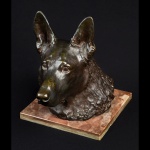 Estatueta de bronze patinado representando busto de cachorro. Base de mármore rosado. 30 x 18 x 28 cm.