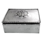 Caixa retangular para cigarros, de mesa, em prata alemã ou austríaca lisa, ornada com friso de grãos centralizando rosácea estilizada. Contrastes do século XIX e marca de prateiro. 4 x 13 x 9 cm. Peso 382 gramas.