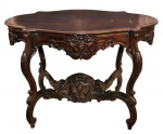 Mesa de apresentação em madeira nobre. Apresenta tampo ovalado e levemente recortado. Saia entalhada com florão central decorada com volutas. Pernas recurvas e entalhadas, interligadas por quatro travessas com florão central. Brasil. Séc. XX. 80 x 115 x 78 cm,