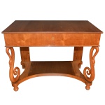 Console Biedermeier em madeira clara com tampo retangular liso apoiado em saia com gavetão à frente. Pernas dianteiras em S, rematadas por cabeças de cisne e apoiadas em plateau recortado sobre pés de bola. 95 x 120 x 66 cm.