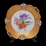 Vintage - Prato para bolo de porcelana alemã da manufatura Rosenthal. A porcelana é branca, ornamentada com uma larga faixa dourada e texturizada e quatro reservas vazadas. O fundo com uma composição floral multicolorida. No fundo marcado: R. C  Rosenthal. Kronach-Germany. Molière. Al Braart Gold. Usada nos anos de 1901 a 1933.