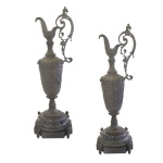Par de elegantes jarras europeias em bronze patinado, ornadas em alto relevo com frisos e adornos em estilo renascentista. Bojos de formato cônico, ornamentados por figuras de putti montados em leões, encimados por bicos longos e recurvos. Alças laterais construídas em volutas. Pés circulares e almofadados apoiados sobre bases quadrangulares recortadas. Séc. XIX. 77 x 25 cm (base).