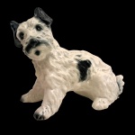 Estatueta na forma de cachorro em porcelana policromada. No fundo marcas da manufatura. 18 x 22 cm.