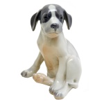 Estatueta na forma de filhote de cachorro, de porcelana Dinamarquesa, policromada. No fundo marca da manufatura Royal Copenhagen. Numerada. 13 x 11 cm.