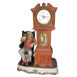 Vintage Collection - Estatueta em cerâmica policromada representando figura de homem sentado em uma cadeira ao lado de um relógio. No fundo selo com as inscrições: Melody in Motion modeled by Seiji Makane. 36 x 23 x 13 cm. Pertenceu ao Espólio de Vitória Dib Bachour.
