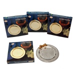 Conjunto de quatro porta copos circulares de metal prateado decorados com laços dourados. 11 cm. Made in Chine. Novos, sem uso. Caixa original. Pertenceu ao Espólio de Vitória Dib Bachour.