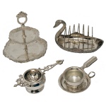 Conjunto de quatro peças para chá em metal prateado, sendo: A) Porta torradas na forma de pato. B) Tea Strainer (coador para chá) com bandeja. 5 x 11 cm (coador). 10 cm (bandejinha circular). C) Tea Strainer (coador para chá). The Bombay Company. 4 x 15 cm. D) Porta petiscos com duas bandejinhas. Pertenceu ao Espólio de Vitória Dib Bachour.