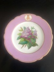 VISCONDE DO RIO PRETO - Prato de porcelana francesa, "Chateau de Pillivuyt". Trata-se do serviço de sobremesa do Visconde do Rio Preto (Domingos Custódio Guimarães). Borda inteiramente em malva entre frisos dourados e extremidade dourada denteada. Ainda na borda, em reserva realçada de dourado, monograma entrelaçado sob coroa de barão. Ao centro, frutos em policromia. Pasta dura. Séc. XIX. 23 cm. Peça do mesmo serviço reproduzida à pág. 315 do Livro "Louça da Aristocracia do Brasil", por Jenny Dreyfus.