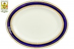 PARAGON - ENGLAND - By Appointment to Her Majesty Queen Elizabeth - Belíssima Travessa Oval Rasa, em fina porcelana inglesa, decoração no padrão clássico com ricos detalhes em ouro e faixa, na tonalidade azul cobalto. Marca da manufatura na base. Dimensões: 2 cm X 26 cm X 20,5 cm (Alt./Comp./Larg.). xl