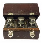 Caixa em couro marrom com três perfumeiros de cristal e tampas provavelmente em prata. Possivelmente Inglaterra, Séc. XIX. 15 x 7 x 10 cm.