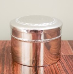 Caixa de toucador, de metal espessurado a prata. Medidas aproximadas: 8 cm de diâmetro x 5 cm de altura.