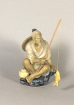figura de pescador em porcelana japonesa policromada tem 16A x 13 de diâmetro e vara de pesca em bambú com peixe em porcelana.