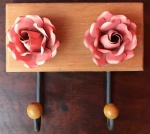 Bela peça em madeira, cabideiro em peroba rosa, com par de rosas em metal dobrado, artesanato mineiro. Com duas alças em ferro pintado arrematadas em esfera de madeira. Altura 18,5cm, Largura 20cm.