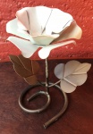 Belo castiçal executado em ferro, artesanato mineiro, com base em espiral arrematada por par de folhas e flor branca no topo em metal dobrado. Altura 16cm.